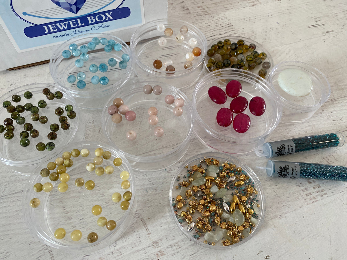 Collection featuring the April 2026 Jewel Loom Jewel Box of gemstones in clear containers on a wooden surface with a 'Jewel Box' packaging.