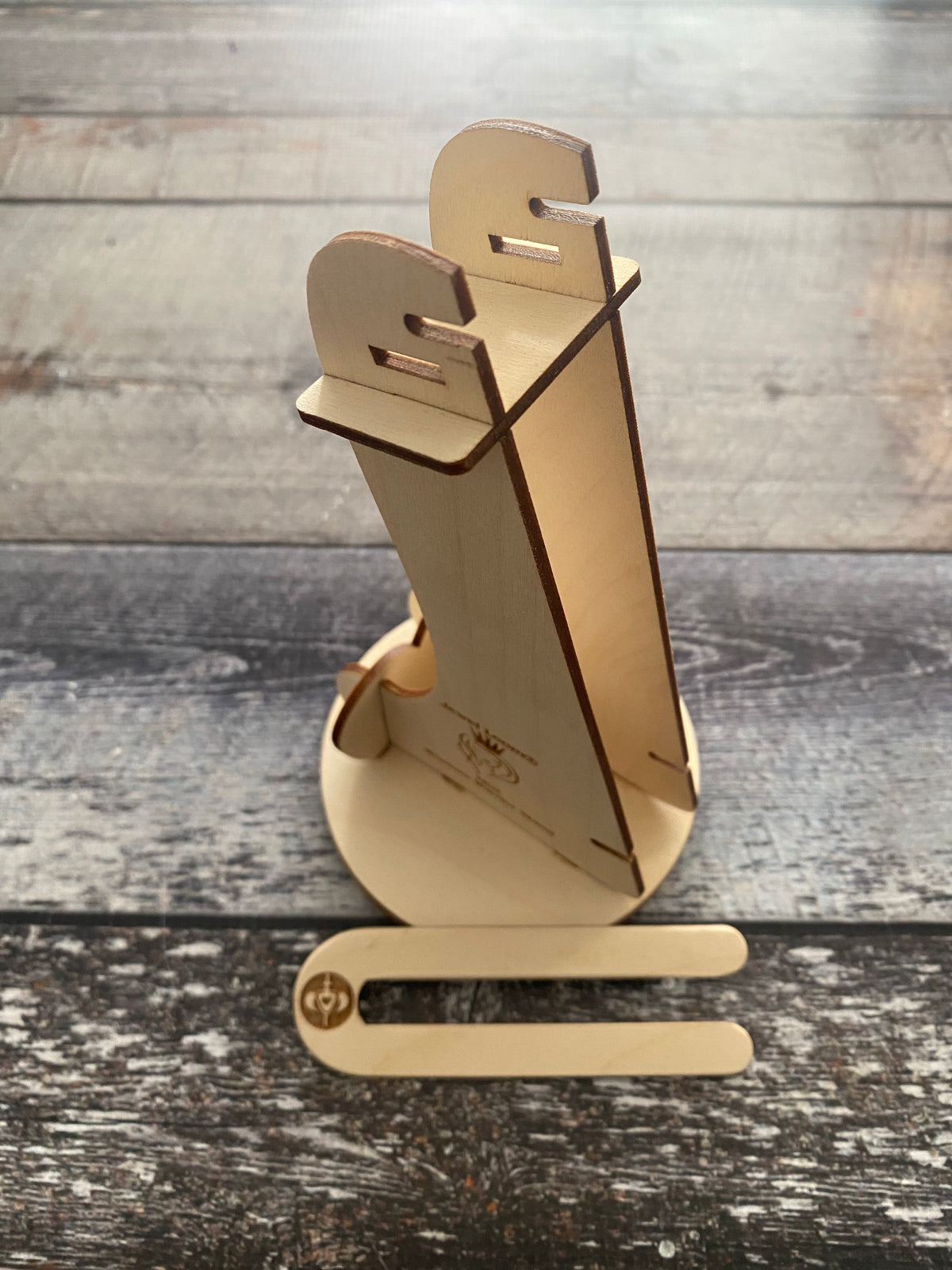 A beige wooden stand designed for a mini wisdom warrior bead loom, displayed on a faux wooden surface.