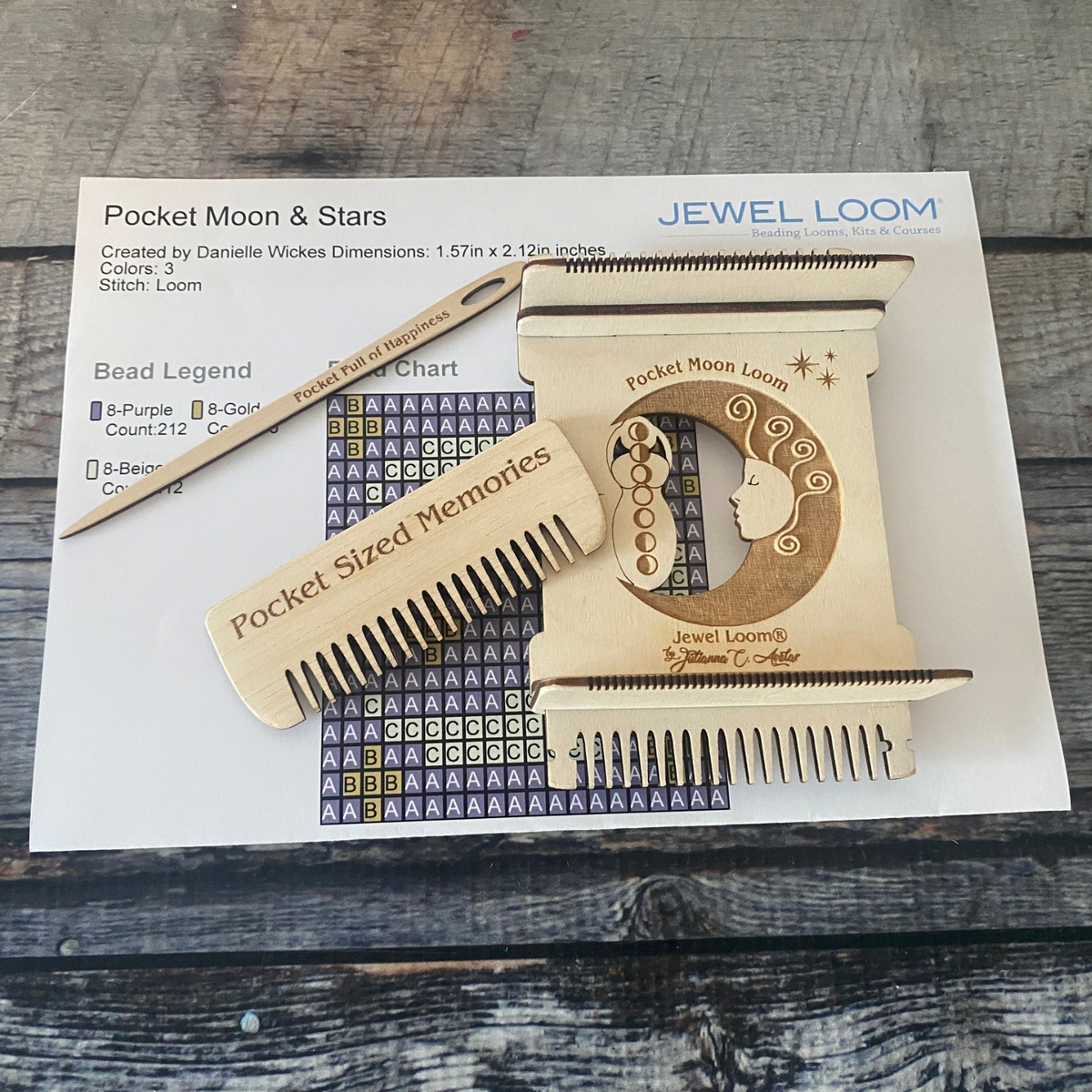 Pocket Moon Loom Kit with comb, needle and Pattern laying on a medium grey background.