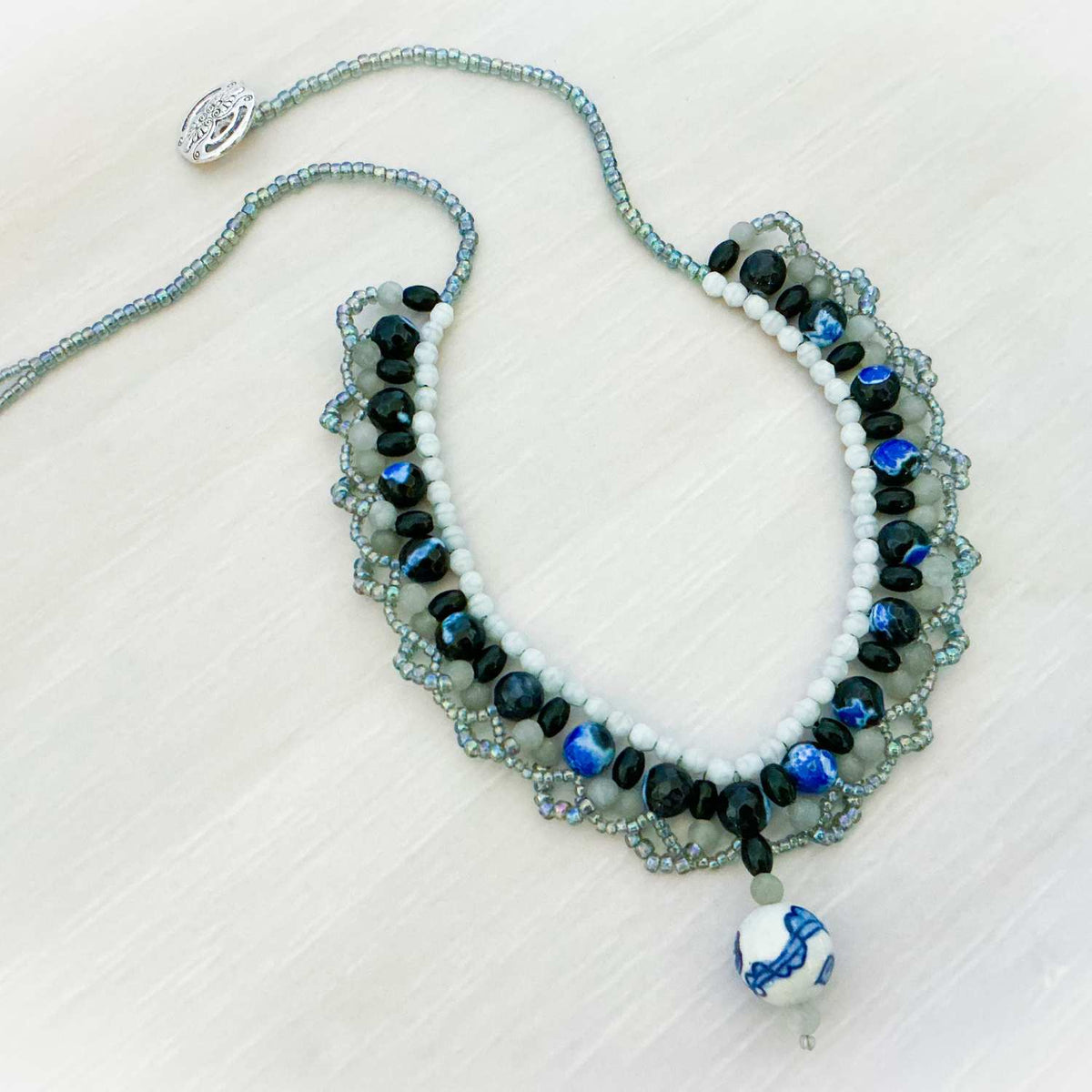 Beaded necklace with blue and black stones on a light background