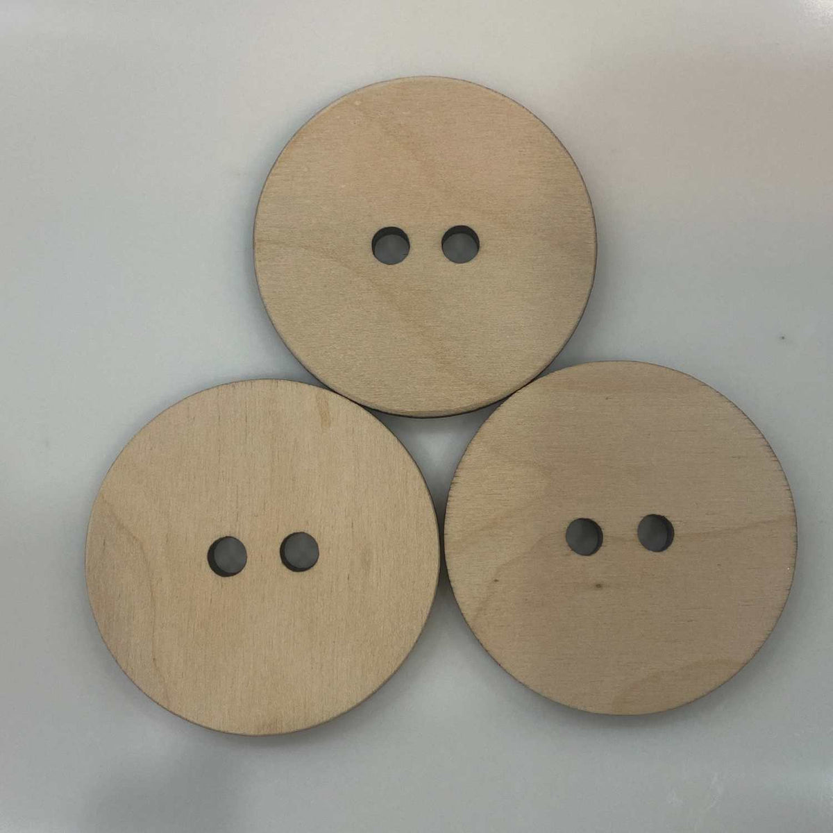 Three wooden buttons Size 2.25" Roound with two holes in each button on a light gray background