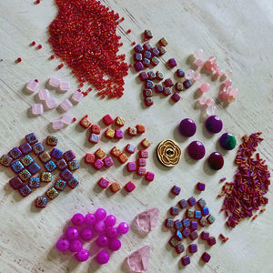 Assorted colorful beads and stones on a light wooden surface