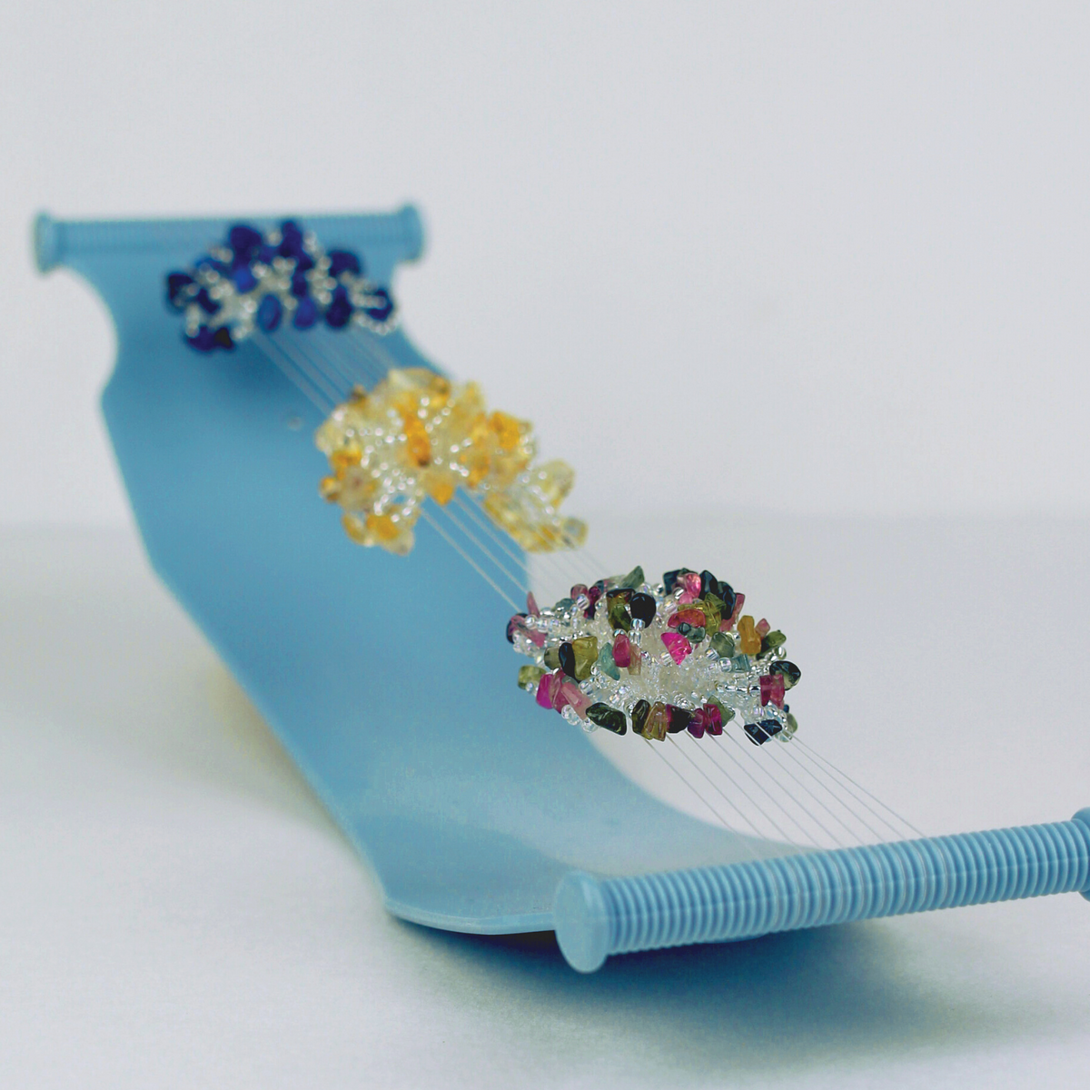 Jewel Loom Bead Loom in Warped position with warp threads and beaded embellishments of Blue, Yelloswand Pink Green 