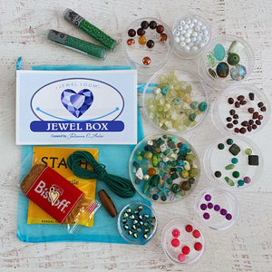 March 2026 Jewel Loom Jewel Box bead kit with over 300 beads including two tubes of TOHO Seed Beads in Size 11/0 and 8/0. The Jewel Box sticker with logo that includes a heart, bag of tea, cookie, hemp cord and a wood button