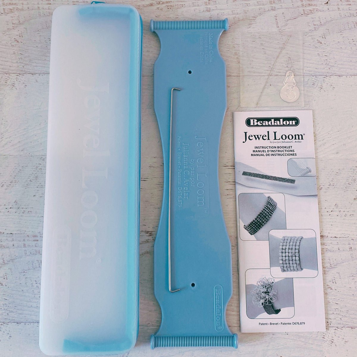 Beadalon Jewel Loom with blue tool and instruction booklet on a light wooden surface
